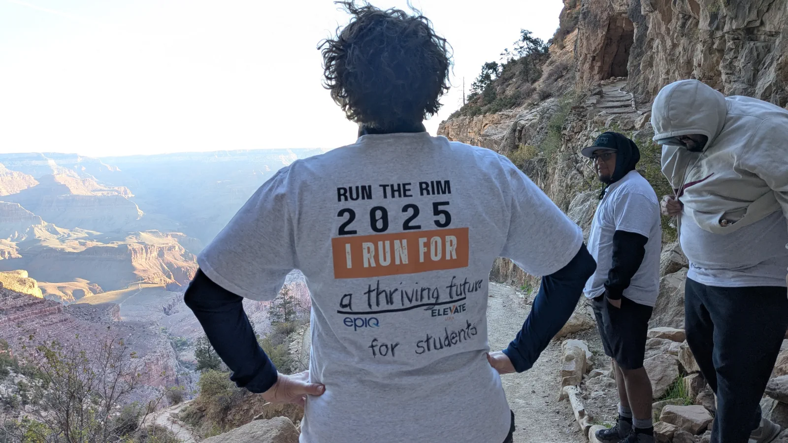Run the Rim participants wearing event shirts on a canyon trail