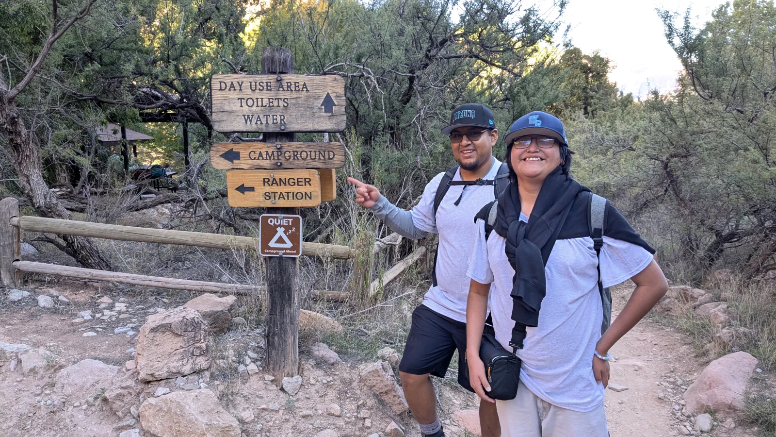 Two Run the Rim participants smiling beside a trail sign